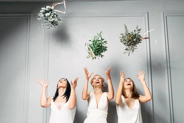 Las damas de honor en vestidos arrojan ramos y ríen — Foto de Stock