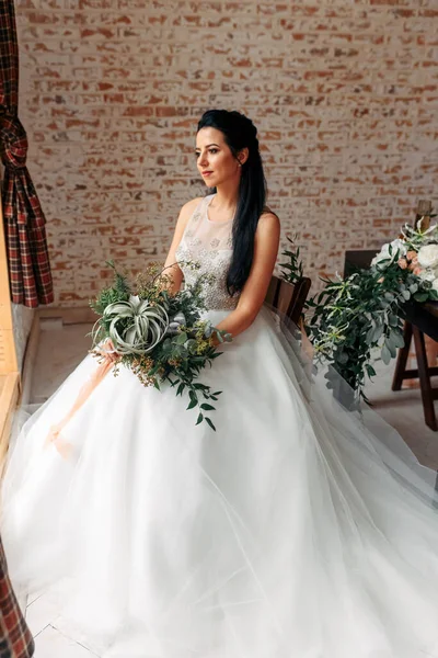 Mooie bruid in een chique jurk met een boeket — Stockfoto