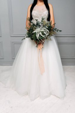 Gelinin uzun ve şık bir elbise içindeki stüdyo fotoğrafı.