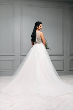 Gelinin uzun ve şık bir elbise içindeki stüdyo fotoğrafı.