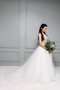 Gelinin uzun ve şık bir elbise içindeki stüdyo fotoğrafı.