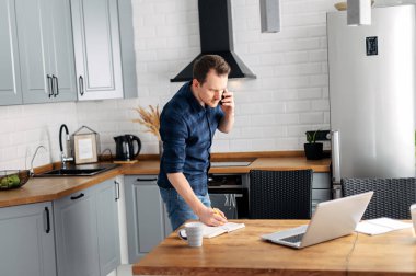 Genç adam evde dizüstü bilgisayar kullanarak çalışıyor..