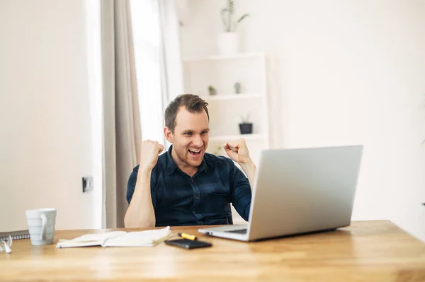 Een man kijkt naar laptop en verheugt zich over het succes van zijn werk — Stockfoto