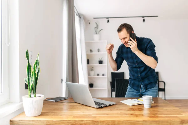 Een man kijkt naar laptop en verheugt zich over het succes van zijn werk — Stockfoto