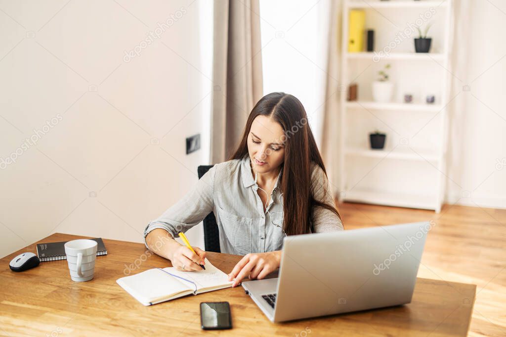 Young woman works from home using laptop.