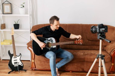 Bir adam gitar dersi, video dersleri kaydediyor.