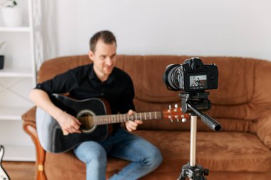 Bir adam gitar dersi, video dersleri kaydediyor.