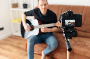Bir adam gitar dersi, video dersleri kaydediyor.