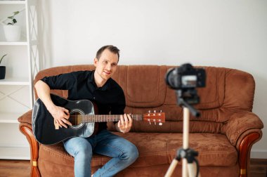 Bir adam gitar dersi, video dersleri kaydediyor.