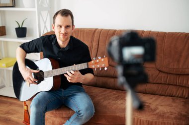 Bir adam gitar dersi, video dersleri kaydediyor.
