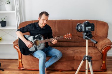 Bir adam gitar dersi, video dersleri kaydediyor.