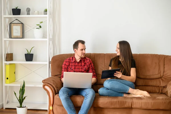 Jovem casal em um sofá com gadgets — Fotografia de Stock