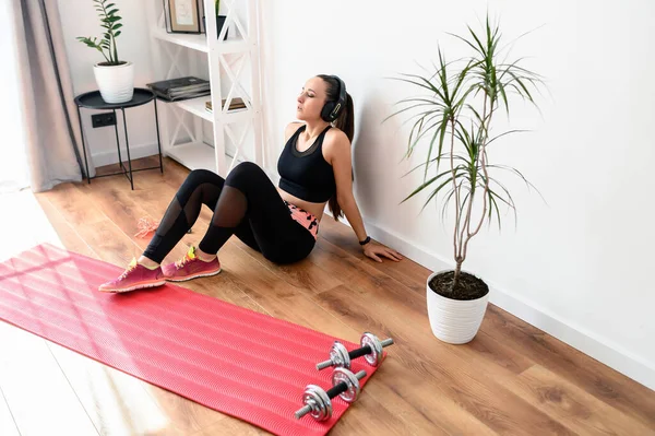 Sportliche Frau mit Kopfhörern müde nach dem Training — Stockfoto