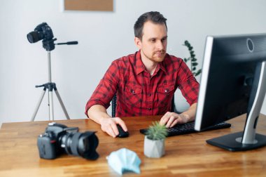 Bilgisayarda tıp maskeli bir fotoğrafçı.