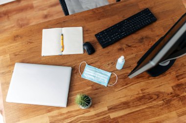 Maske ve dezenfektan masaüstünde, klavyenin yanında.