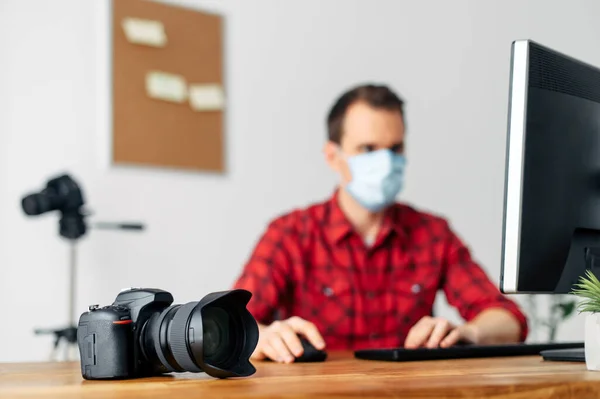Photographer in medicine mask at the computer