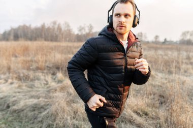 Açık havada kardiyo çalışması. Genç adam koşuyor.