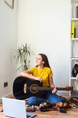Bir kadın gitar çalarken video dersi izliyor.