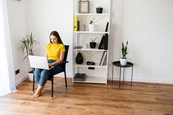 Mujer en un ambiente acogedor en casa con un ordenador portátil — Foto de Stock
