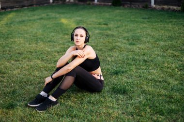 Genç sporcu kadın çimenlerde oturuyor.