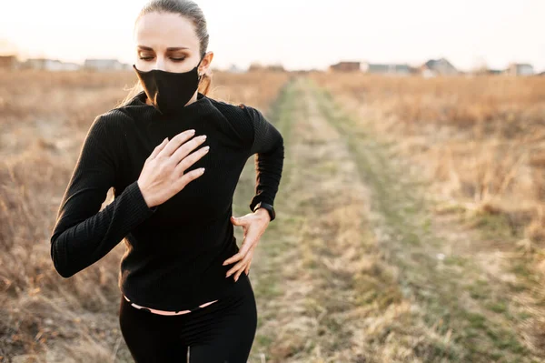 Жінка в загальному чорному спортивному одязі біжить на відкритому повітрі — стокове фото
