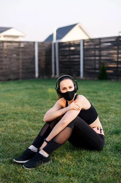 Γυναίκα με ιατρική μάσκα κάθεται στο γρασίδι — Φωτογραφία Αρχείου