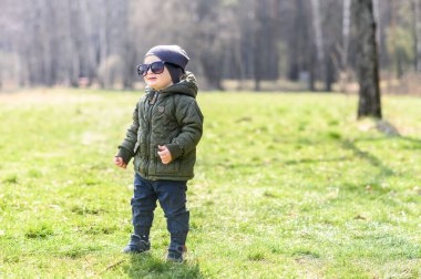Komik çocuk güneş gözlükleriyle yeşil çimlerin üzerinde duruyor.