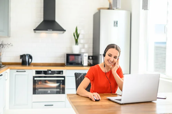 Junge Frau arbeitet von zu Hause aus mit Headset und Laptop — Stockfoto