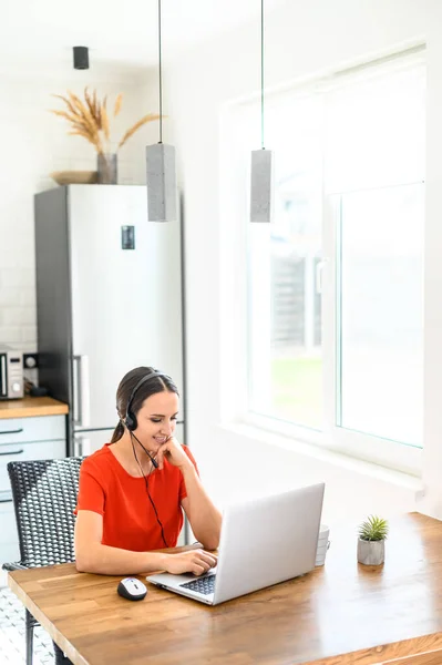 Junge Frau arbeitet von zu Hause aus mit Headset und Laptop — Stockfoto