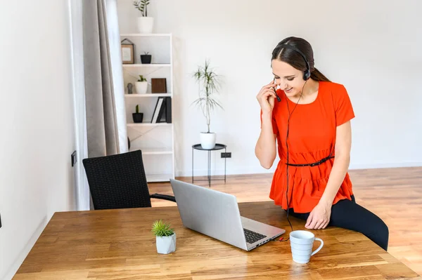 Frau arbeitet von zu Hause aus mit Headset und Laptop — Stockfoto