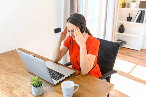 Mulher trabalha em casa usando fone de ouvido e laptop — Fotografia de Stock