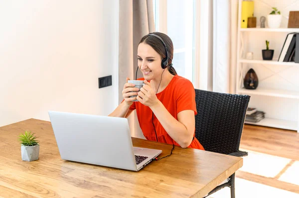 Frau arbeitet von zu Hause aus mit Headset und Laptop — Stockfoto