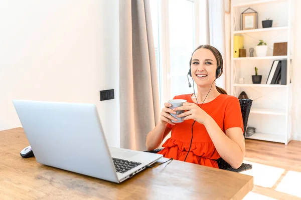 Frau arbeitet von zu Hause aus mit Headset und Laptop — Stockfoto