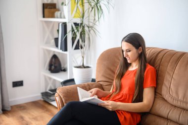 Kadın kanepede oturur ve kitap okur.