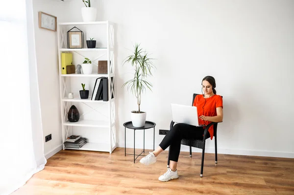 Frau arbeitet zu Hause mit Headset und Laptop — Stockfoto
