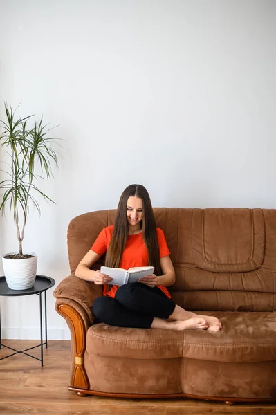 Женщина сидит на диване и читает книгу — стоковое фото