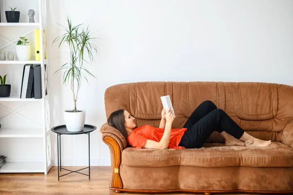 Женщина лежит на диване и читает книгу — стоковое фото