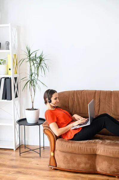 Жінка працює з дому за допомогою ноутбука та гарнітури — стокове фото