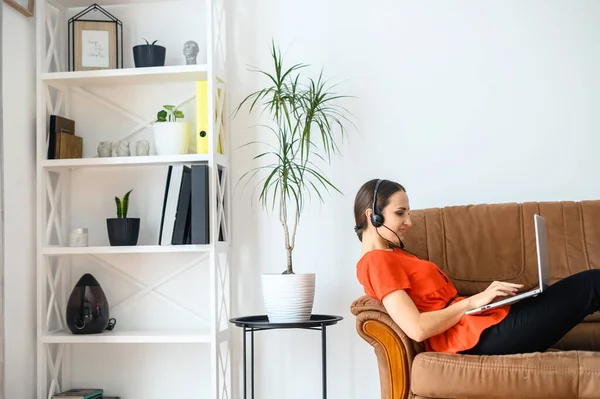 Vrouw werkt thuis met laptop en headset — Stockfoto
