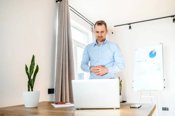 A young businessman in a smart casual uses laptop