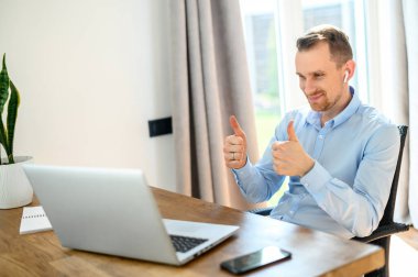 Hava podlu resmi tişörtlü bir adam dizüstü bilgisayar kullanıyor.