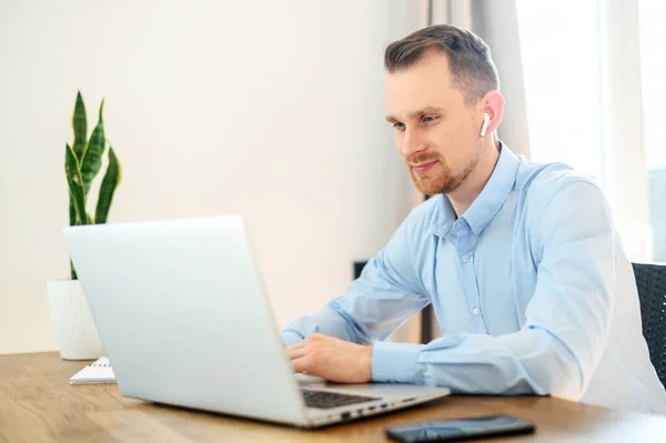 Guy dans une chemise formelle avec des aéropodes utilise un ordinateur portable — Photo