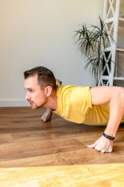 Genç bir adam antrenman yapıyor, şınav çekiyor.