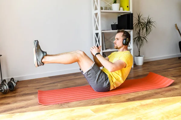 A young guy doing sit-ups exercise at home — Stock Photo, Image