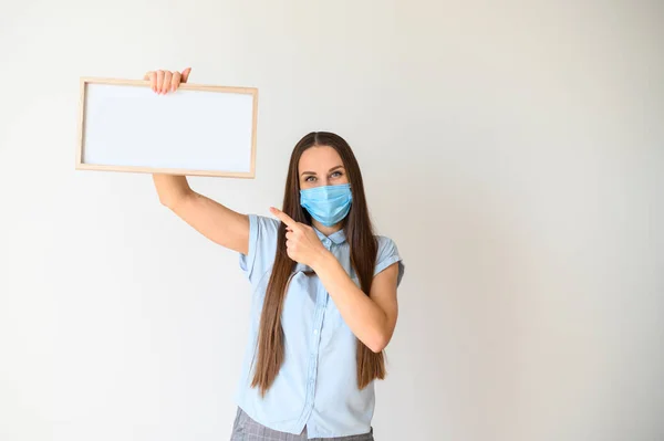 Frau mit medizinischer Maske steht mit leerem Brett — Stockfoto