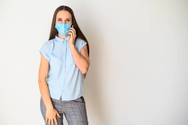 Молода жінка в медичній масці зі смартфоном — стокове фото