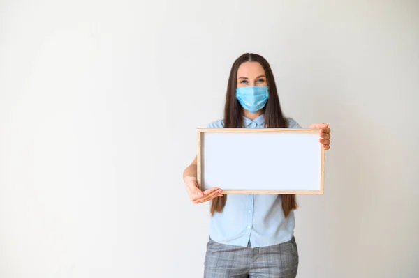 Frau mit medizinischer Maske steht mit leerem Brett — Stockfoto