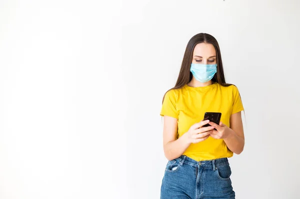 Жінка в медичній масці показує зі смартфоном — стокове фото