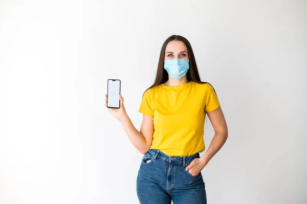 Жінка в медичній масці показує екран телефону — стокове фото