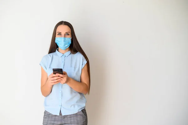 Junge Frau mit medizinischer Maske und Smartphone — Stockfoto